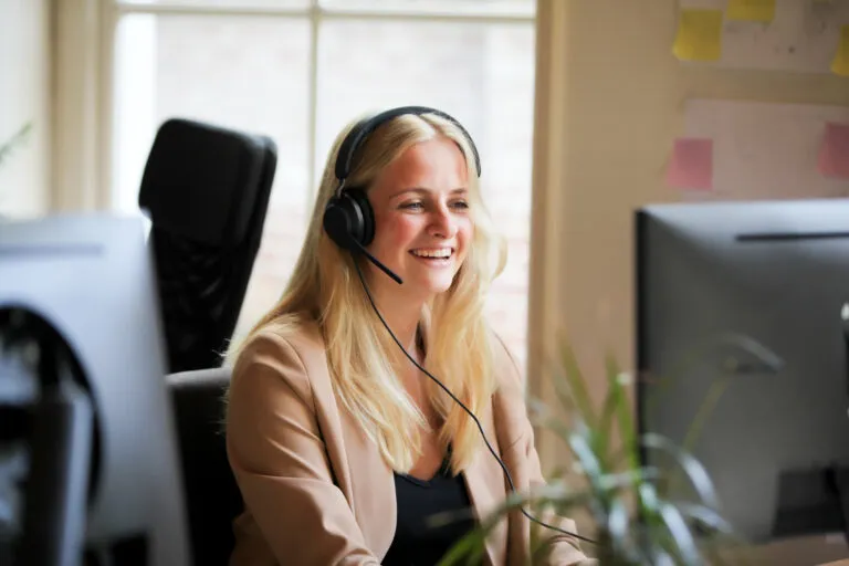 Een medewerkster van Voja Travel met headset beantwoordt een telefoontje van een reiziger achter haar computer